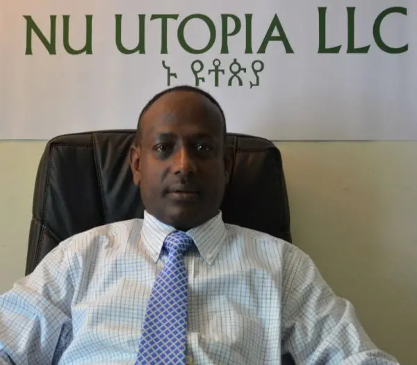 Man sitting under "NU Utopia LLC" sign.
