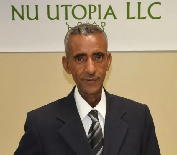 Man in suit standing before company sign.